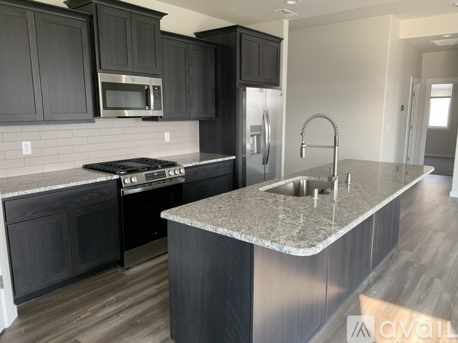 A kitchen with dark cabinets and a granite countertop.