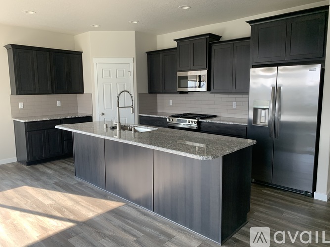A modern kitchen with dark cabinets and stainless steel appliances.