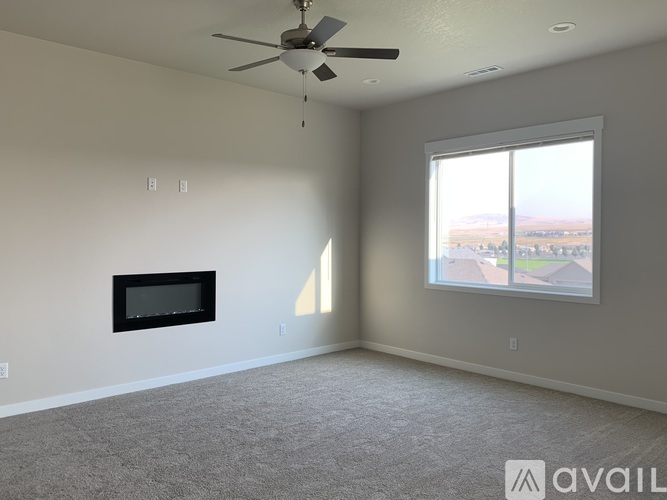 A spacious living room with a ceiling fan and a flat-screen TV mounted on the wall.