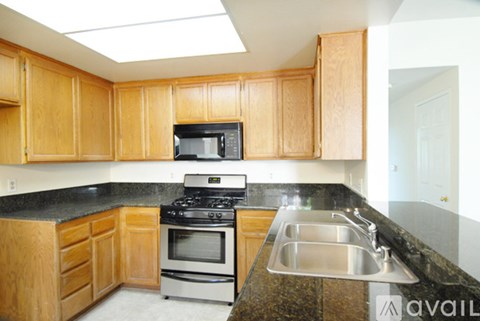 A kitchen with wooden cabinets and a black countertop.
