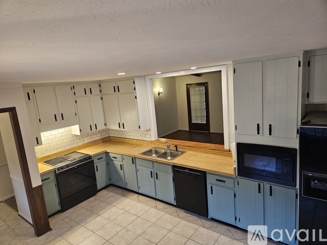 A kitchen with white cabinets and black appliances.