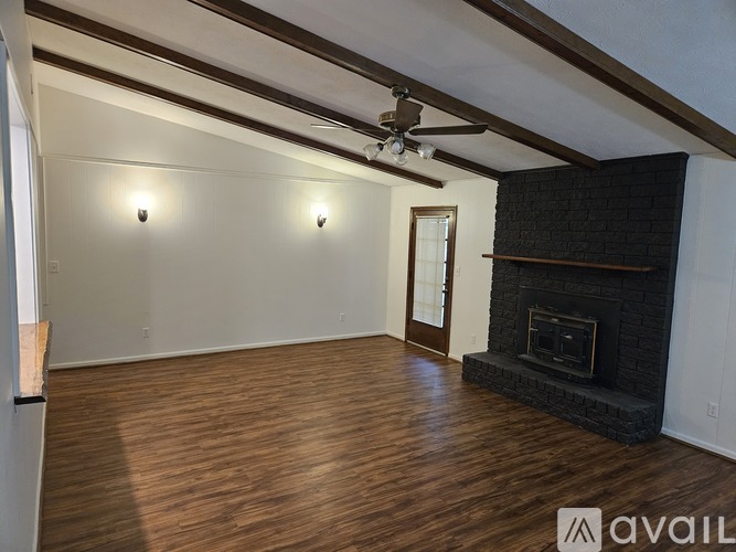 A spacious living room with a fireplace and a ceiling fan.