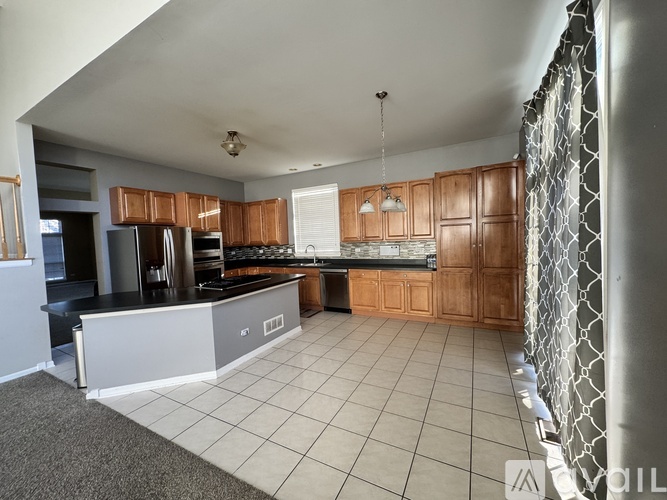 A kitchen with wooden cabinets and a black refrigerator.