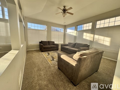 A living room with a brown couch and a ceiling fan.