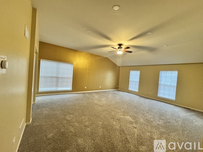 A spacious room with a ceiling fan and carpeted floor.