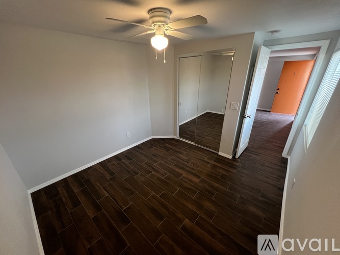 A room with a ceiling fan and wooden flooring.