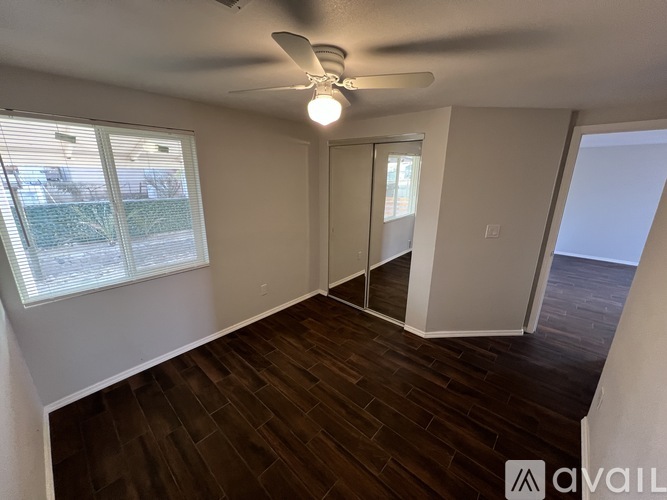 A room with a ceiling fan and sliding glass doors.