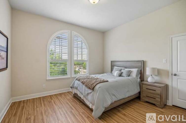 A bedroom with a large bed and a window with shutters.