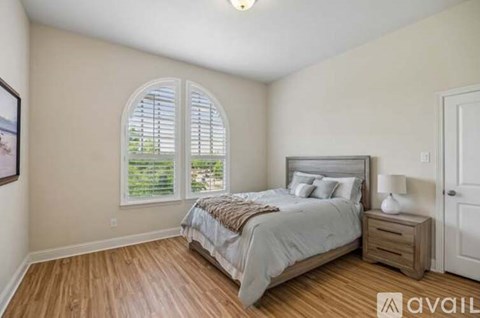 A bedroom with a large bed and a window with shutters.