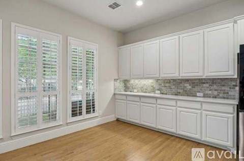 A kitchen with white cabinets and a brick backsplash.