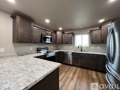 A kitchen with dark wood cabinets and a marble countertop.