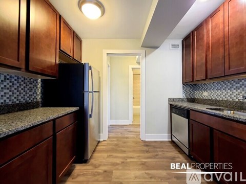 A kitchen with dark wood cabinets and a black refrigerator.