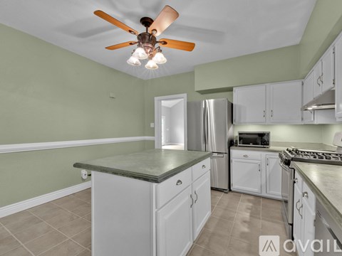 A kitchen with white cabinets and a stainless steel refrigerator.