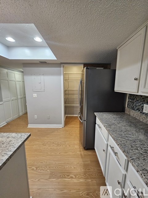 A kitchen with a black refrigerator and white cabinets.