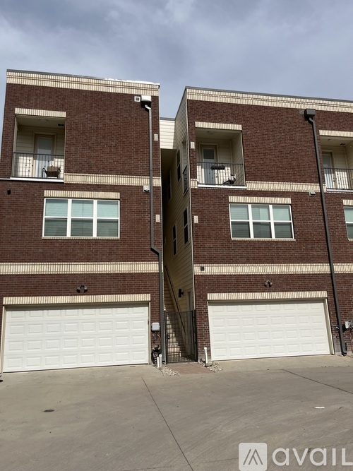 Two red brick buildings with white garage doors in front.
