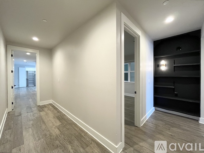A spacious room with wooden flooring and white walls.
