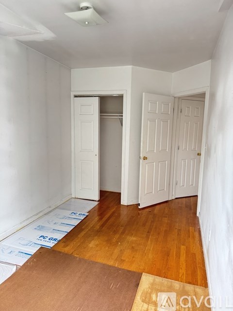 A room with wooden floors and white walls with two doors.