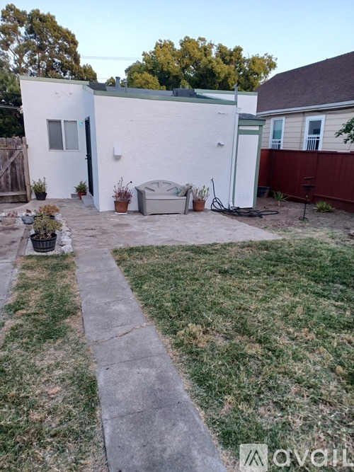 A backyard with a white shed and a concrete walkway.