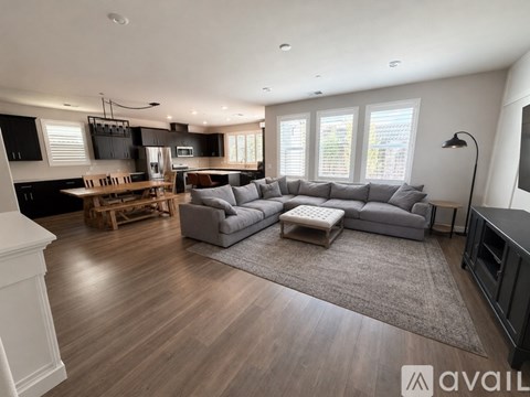 A modern living room with a grey sofa and wooden flooring.