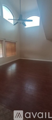 A room with a ceiling fan and wooden flooring.
