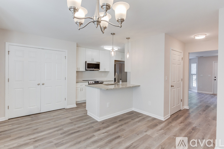 A kitchen with white cabinets and a wooden floor.