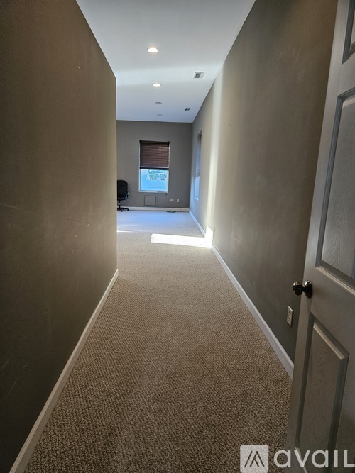 A hallway with a carpeted floor and a door on the right side.