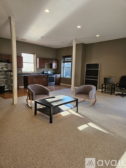 A living room with a brown carpet and a black coffee table.