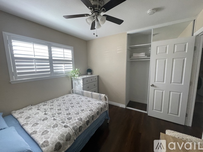 A bedroom with a bed, dresser, and a ceiling fan.