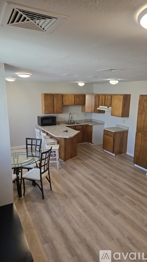 A kitchen with wooden cabinets and a dining table with chairs.