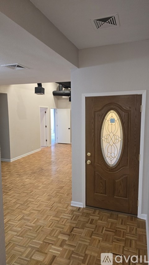 A room with a wooden floor and a brown door with a glass window.