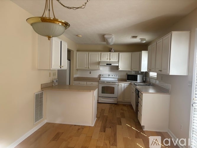 A kitchen with white cabinets and wooden floors.