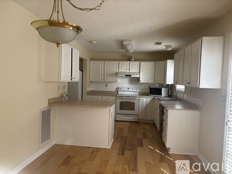 A kitchen with white cabinets and wooden floors.