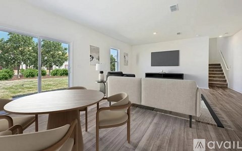 A modern living room with a TV, sofa, and a round table with chairs.