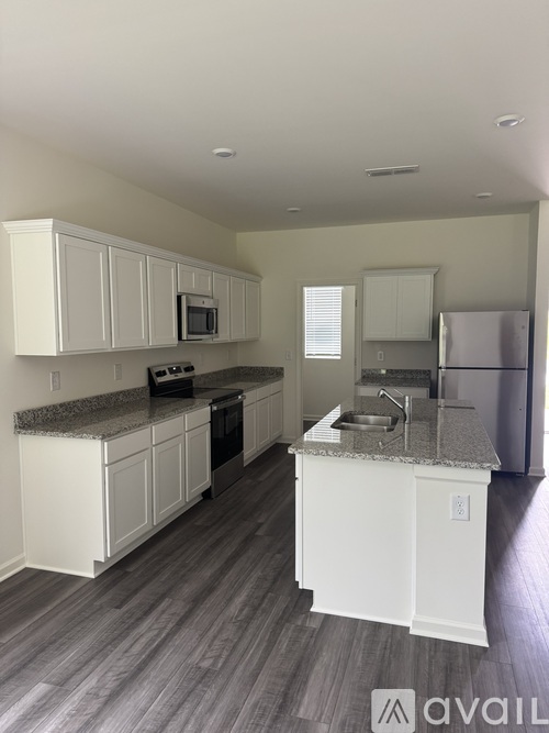 A kitchen with white cabinets and a granite countertop.
