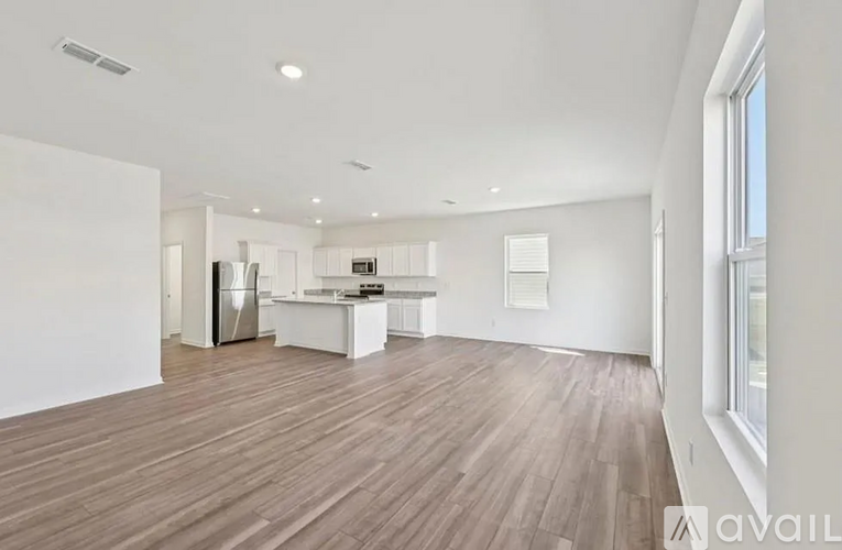 A spacious room with wooden flooring and white walls.