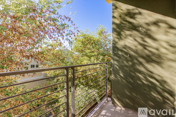 A balcony with a metal railing and trees in the background.