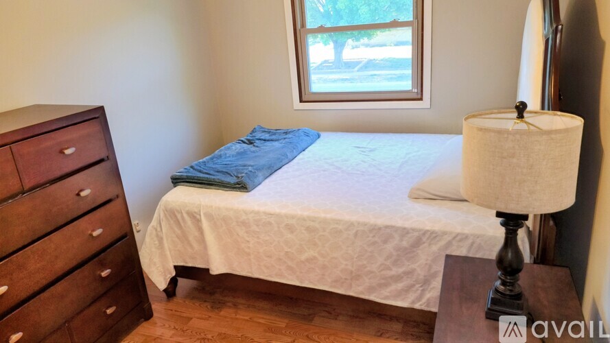 A bedroom with a bed, nightstand, and lamp.