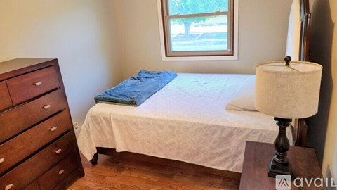 A bedroom with a bed, nightstand, and lamp.