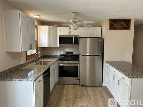 A kitchen with white cabinets and a granite countertop.