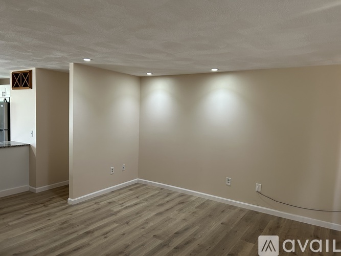 A spacious room with wooden flooring and beige walls.