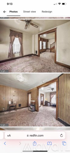 A room with a ceiling fan and a window with curtains.