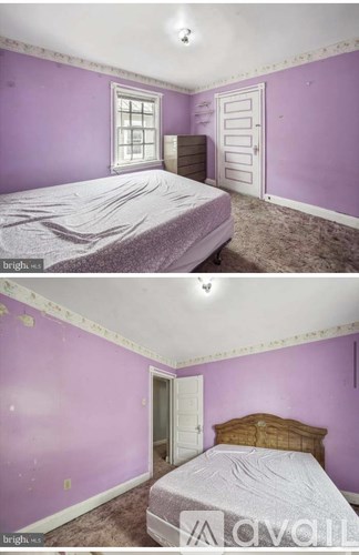 A bedroom with purple walls and a bed.