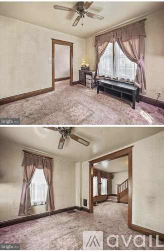 A living room with a couch, a fan, and a staircase.