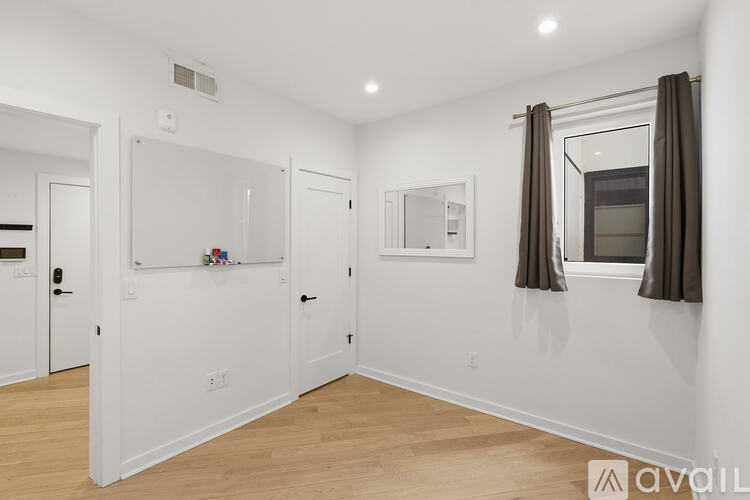 A sparsely furnished room with a window and a mirror.