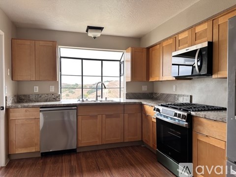 A kitchen with wooden cabinets and a large window.