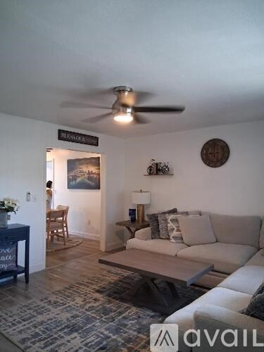 A living room with a couch, a table with a lamp, and a painting on the wall.