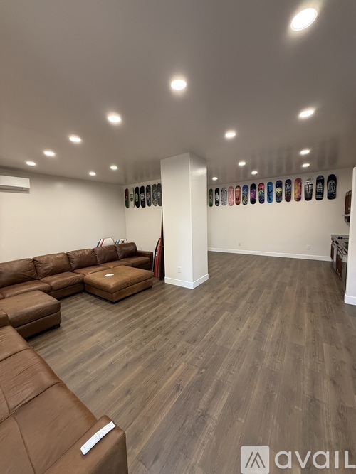A living room with brown leather furniture and a wall of shoes.