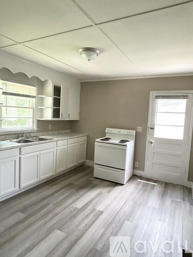 A kitchen with white cabinets and a white stove top oven.