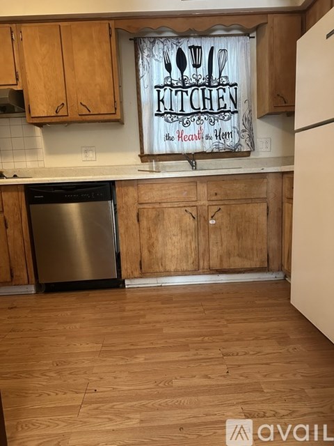 A kitchen with wooden cabinets and a sign that says "Kitchen".