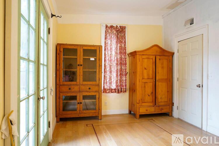 A room with a wooden cabinet, a glass door cabinet, and a white door.